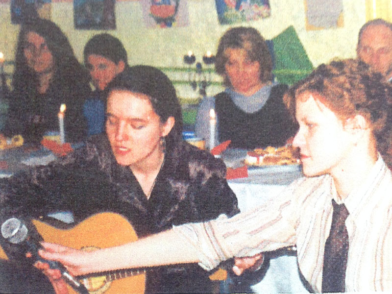 a girl with a guitar surrounded by youngsters